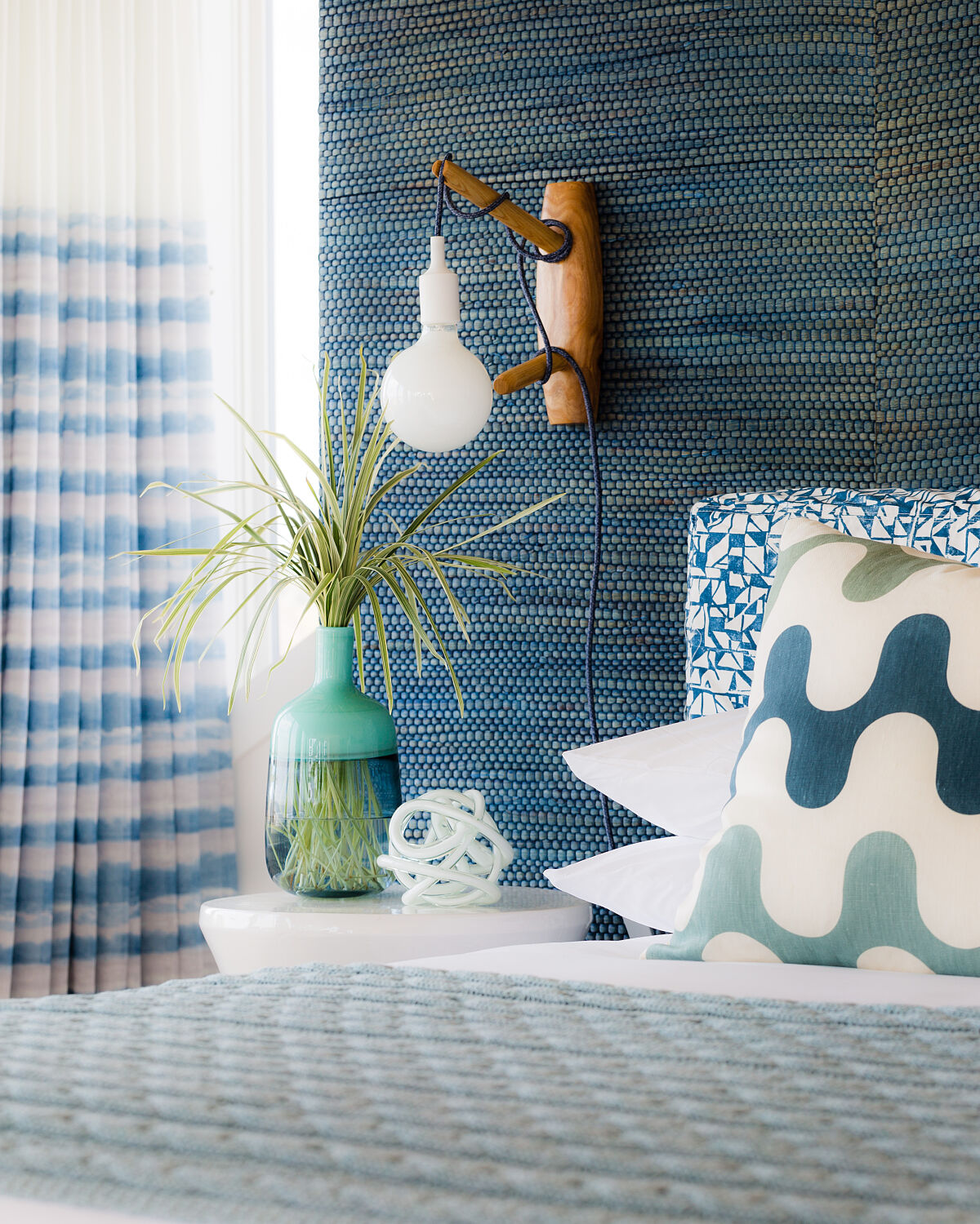 Close up of lamp, headboard, side table and bed pillows